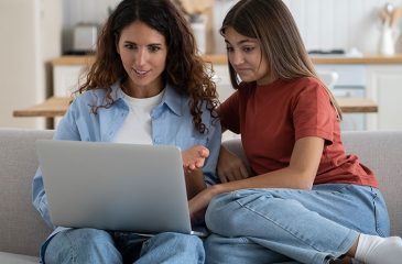 mom and daughter look at laptop