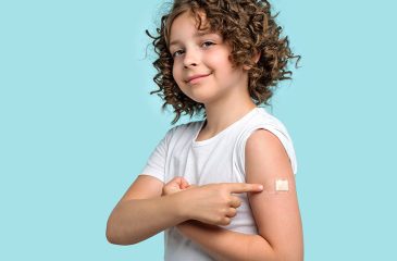 child pointing to bandaid covering immunization